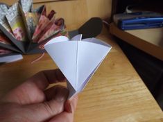 a hand holding an origami piece on top of a wooden table next to other items