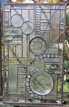 a decorative glass window sitting on top of a wooden bench in front of some plants