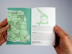 a person holding up a book with an image of a map in the middle and green lettering