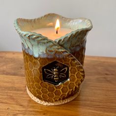 a candle that is sitting on a table with a bee in it's center