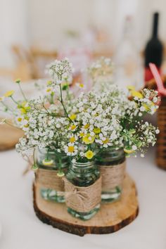 mason jars filled with daisies and baby's breath are tied to wood slices