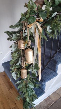 a christmas wreath with bells hanging from it's side on the stairs next to a banister