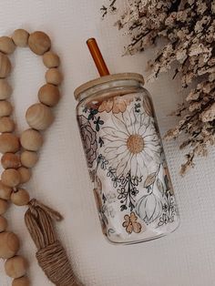 a wooden bead necklace next to a mason jar with a flower design on it