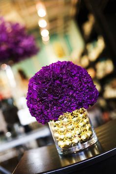 purple and gold flowers in a vase on a table