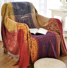 a chair with a blanket on it in front of a window and a footstool