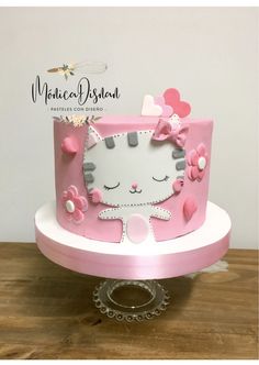 a hello kitty cake with pink and white icing on a wooden table next to a wall