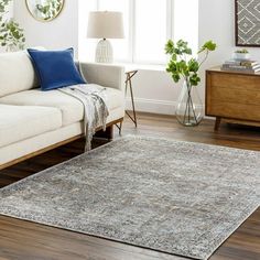 a living room with a couch, chair and rug on the hardwood floor in front of a window