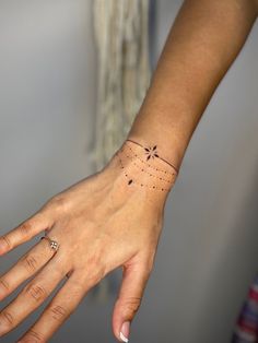 a woman's hand with a small tattoo on her left wrist and the other arm