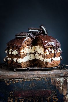 a chocolate cake with white frosting and oreo cookies on top is cut in half