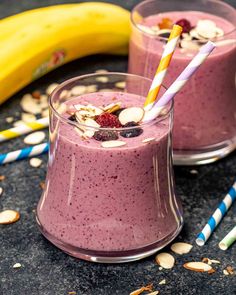 two glasses filled with smoothie next to bananas and almonds on a table top