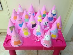 pink party hats with peppa pig characters on them are sitting on a pink table