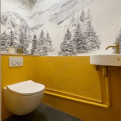 a bathroom with yellow and white wallpaper has a toilet, sink and mirror in it