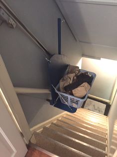 a laundry basket sitting on top of a flight of stairs next to a light fixture