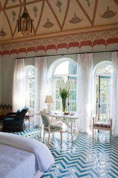 a living room filled with furniture next to two large windows covered in white drapes