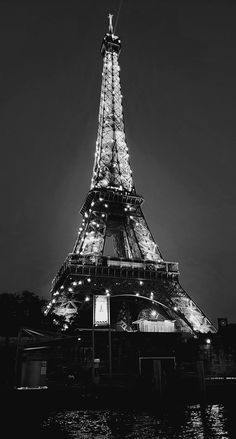 the eiffel tower lit up at night in black and white with its lights on