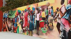 a large mural on the side of a building with people walking by and carrying buckets