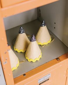 three yellow and silver cones sitting on top of a shelf