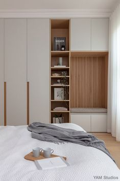 a white bed sitting in a bedroom next to a wooden book shelf filled with books