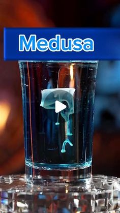 a glass with an image of a person in it on top of a table next to a medusa logo