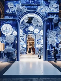 people are walking through an archway decorated with blue and white floral wallpapers on the walls