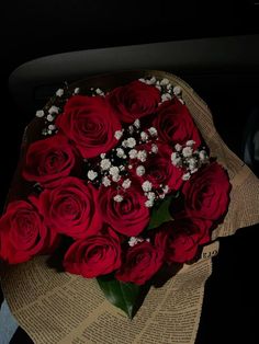 a bouquet of red roses sitting on top of an old book with baby's breath