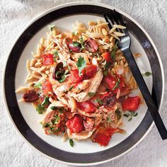 a white plate topped with pasta and meat covered in tomato sauce next to a fork