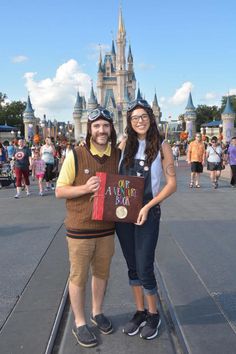 a man and woman pose for a photo in front of the castle at disney world