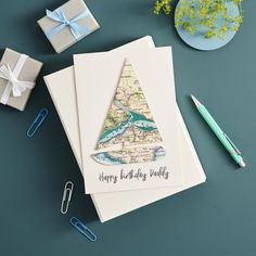 there is a card with a christmas tree on it next to some other cards and pens