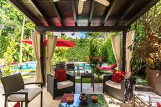 an outdoor living area with couches, tables and umbrellas