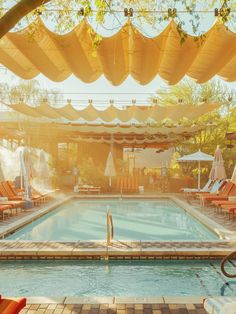 an outdoor swimming pool with chairs and umbrellas