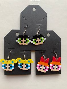 four pairs of earrings made out of legos are shown in front of a tag