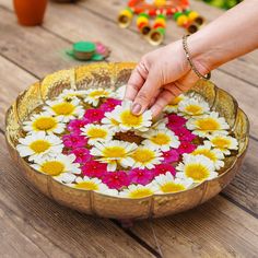 a person is placing flowers in a bowl