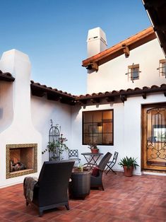 a patio with chairs, tables and a fire place in the middle of it that has a tiled floor