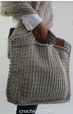 a person holding a knitted bag in their hand and the bottom half of it