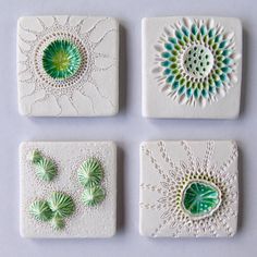 four white and green ceramic coasters sitting on top of a table