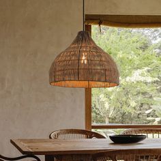 a dining room table with chairs and a basket light hanging from the ceiling over it