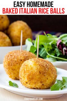 two baked italian rice balls with toothpicks on them and salad in the background