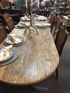 a wooden table with plates and place settings on it in a room filled with furniture