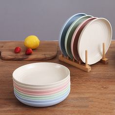 a stack of plates sitting on top of a wooden table next to a cutting board