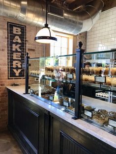 a bakery with lots of baked goods on display behind the counter and lights hanging from the ceiling