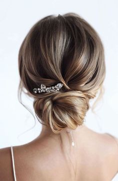 a woman with her hair in a low bun, wearing a bridal headpiece