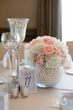 the table is set with flowers and candles for an elegant wedding reception in white, pink and silver