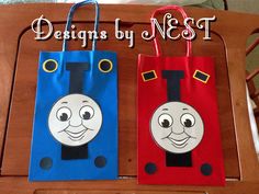 two bags with thomas the train faces on them sitting on a wooden table next to each other