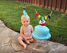 a baby sitting in front of a birthday cake