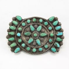 an old silver and turquoise colored broochle on a white background, with lots of stones in the center