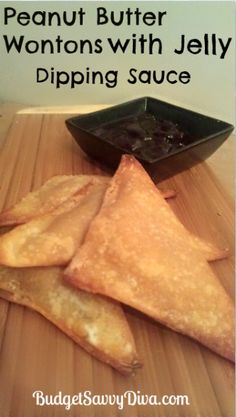 three pieces of food sitting on top of a wooden cutting board next to a bowl of dipping sauce