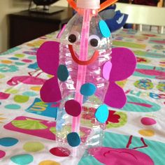 a plastic bottle with a face on it sitting on a table covered in polka dots