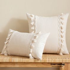 two white pillows sitting on top of a wooden bench