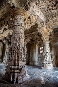 an intricately carved stone pillar in the middle of a room with columns and pillars