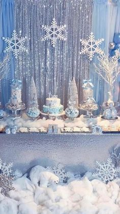 a table topped with lots of blue and white snowflakes next to balloons in the air